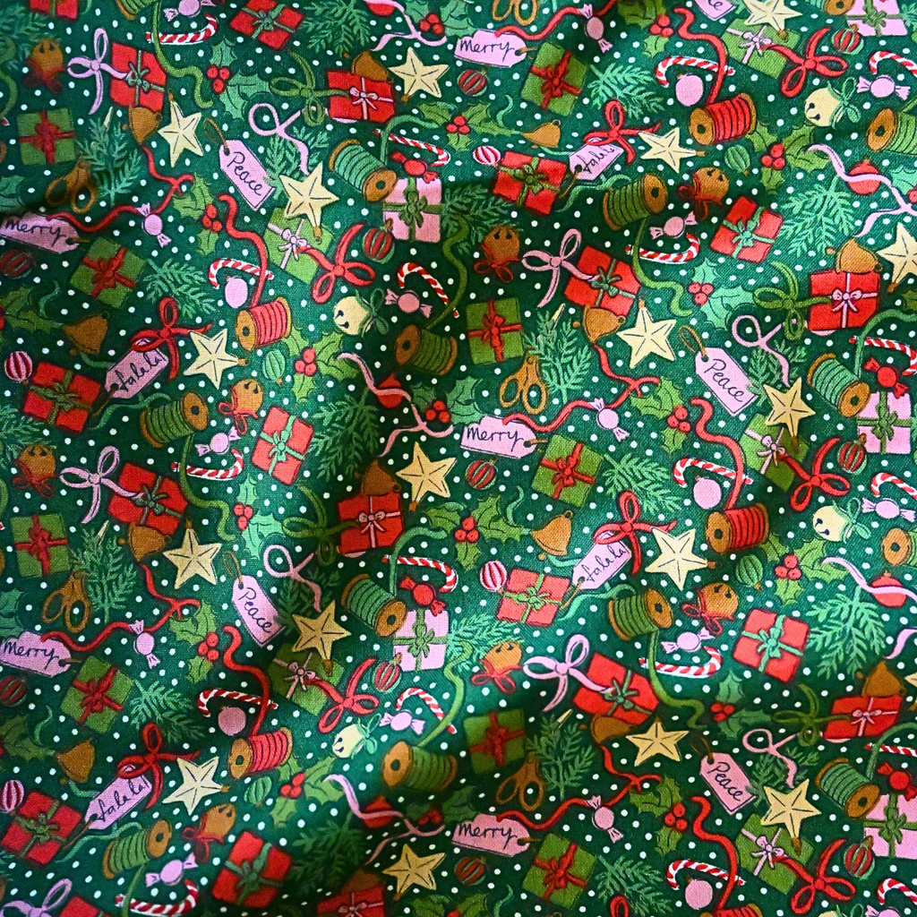 Christmas-themed fabric with various festive elements on a green background