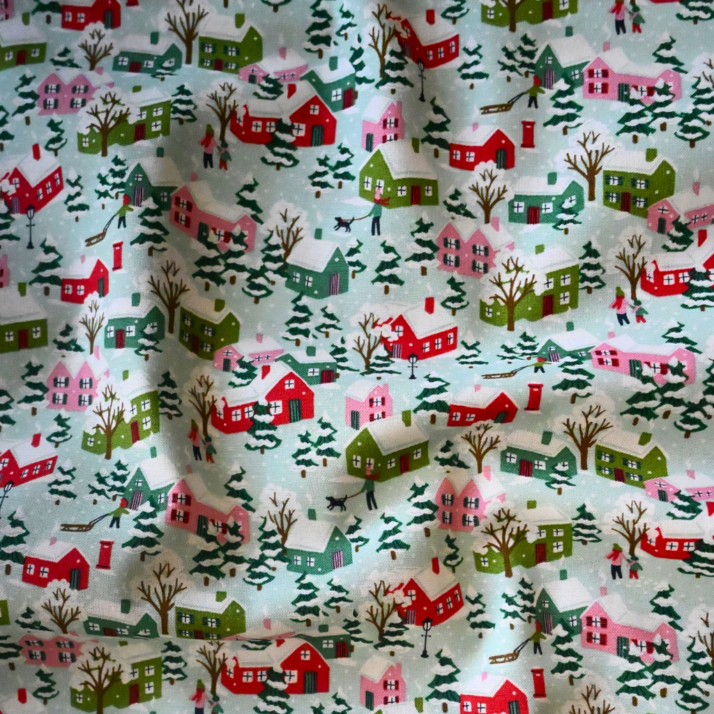 Fabric with a holiday village pattern featuring houses and trees.