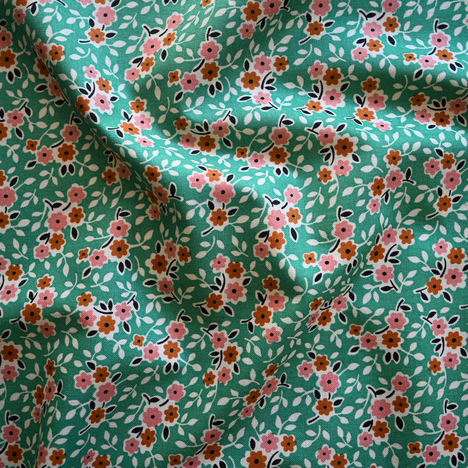 Floral fabric pattern with small flowers on a green background