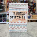 Essential Embroidery Stitches Card Deck by Betty Barnden — 50-card embroidery stitch reference with booklet. Craft shop background (blurred).