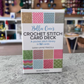 Bella Coco's Crochet Stitch Card Deck — 52-card pocket stitch library for crocheters. Packaged, blurred craft shop background