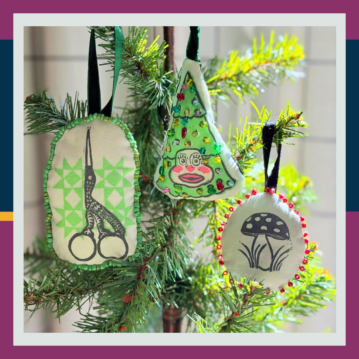 Promotional image for a 'Block Printed Ornaments Workshop' with Kelly.
Three handmade fabric Christmas tree ornaments hanging on a green pine tree branch. The ornaments are cream-colored with green, red, and black embroidered details, featuring a pair of scissors, a Christmas tree, and a mushroom.