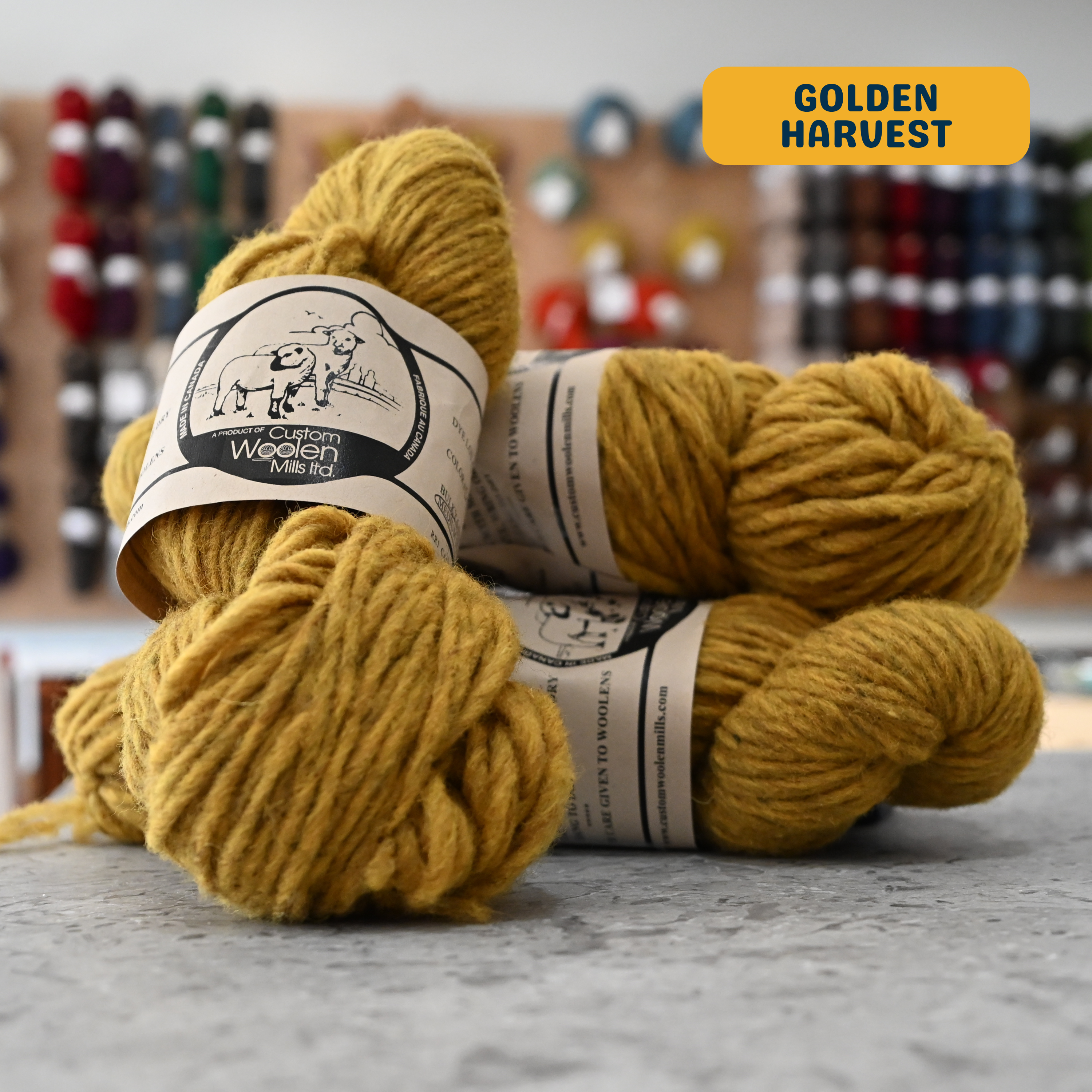 112g yelllow (golden harvest) Canadian wool bulky yarn, 'Custom Woolen Mills' label visible, craft shop background (blurred)