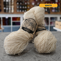 113g natural undyed white Canadian wool fingering yarn, 'Custom Woolen Mills' label visible, craft shop background (blurred)