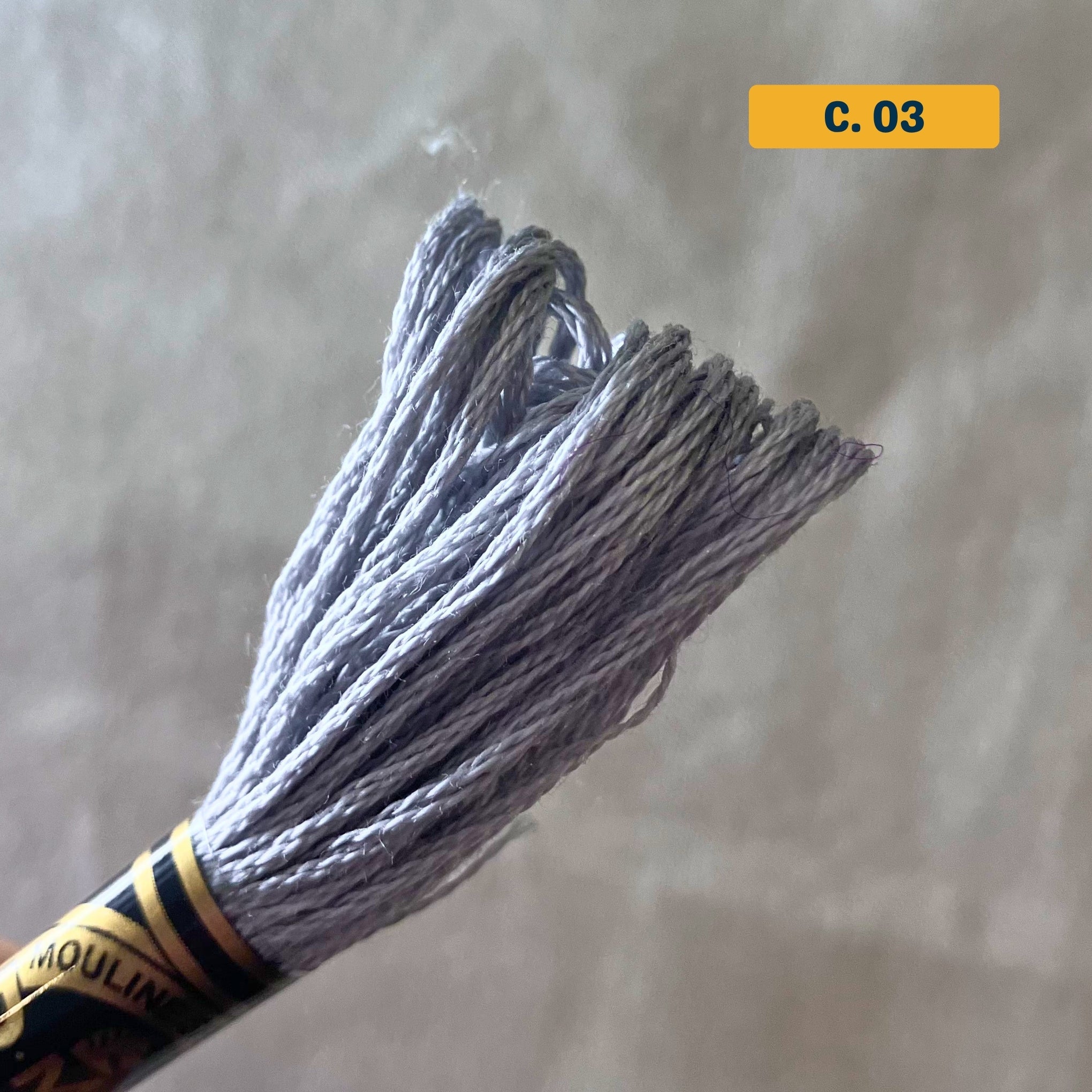 DMC 6-Strand Cotton Embroidery Floss – 03 Medium Grey – 8m skein, 100% Egyptian cotton. Fabric background (blurred).