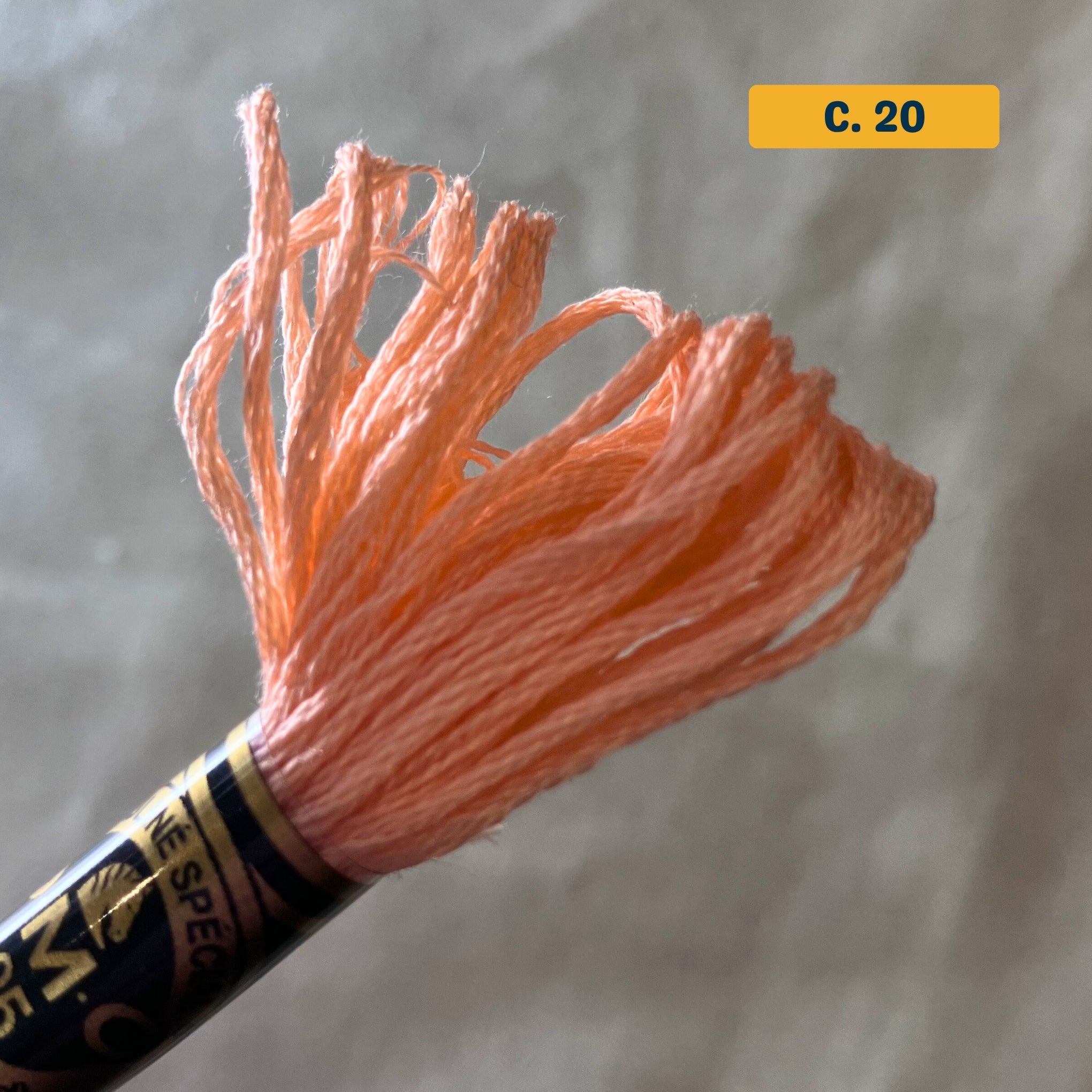 DMC 6-Strand Cotton Embroidery Floss –20 Peach – 8m skein, 100% Egyptian cotton. Fabric background (blurred).