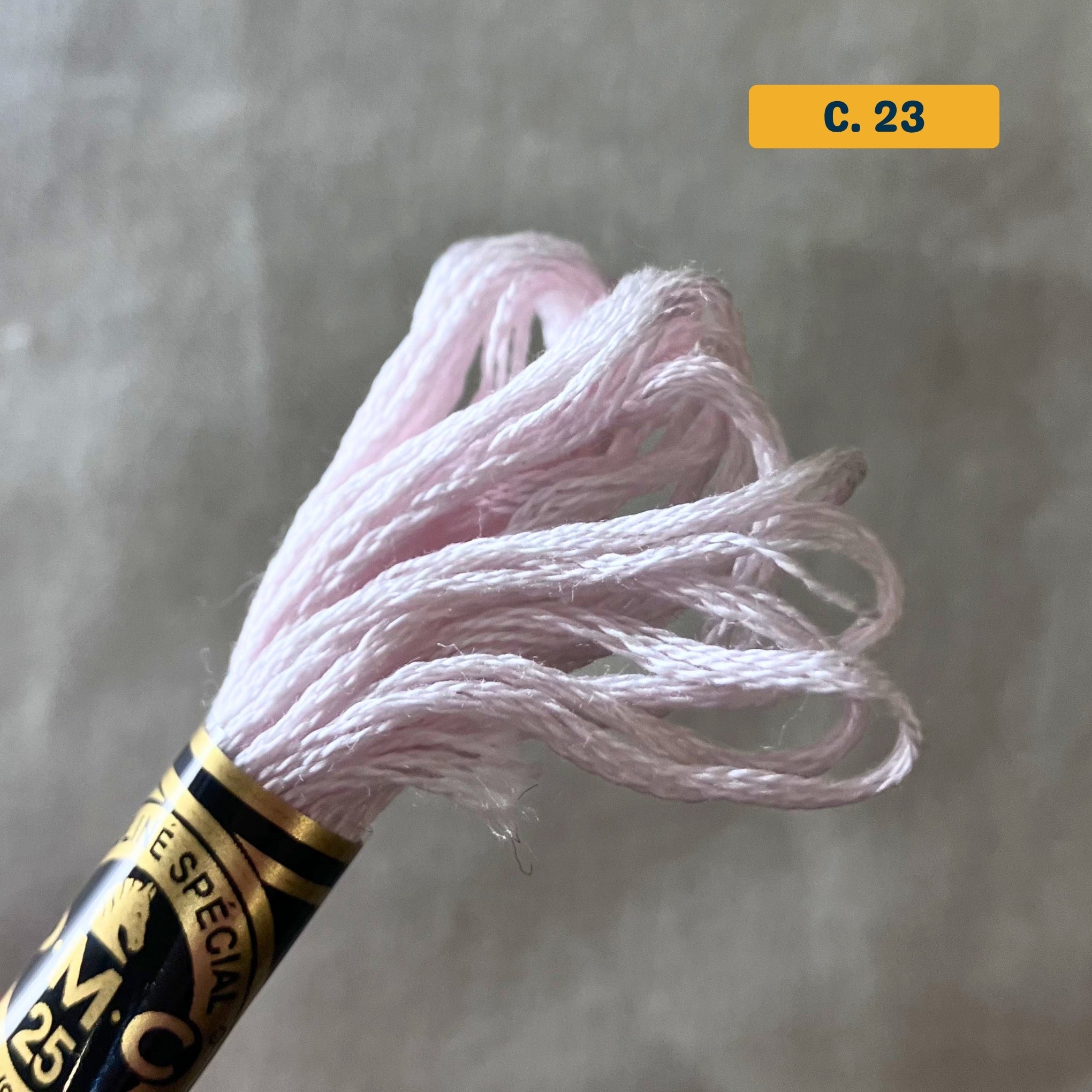 DMC 6-Strand Cotton Embroidery Floss – 23 Very Pale Pink – 8m skein, 100% Egyptian cotton. Fabric background (blurred).