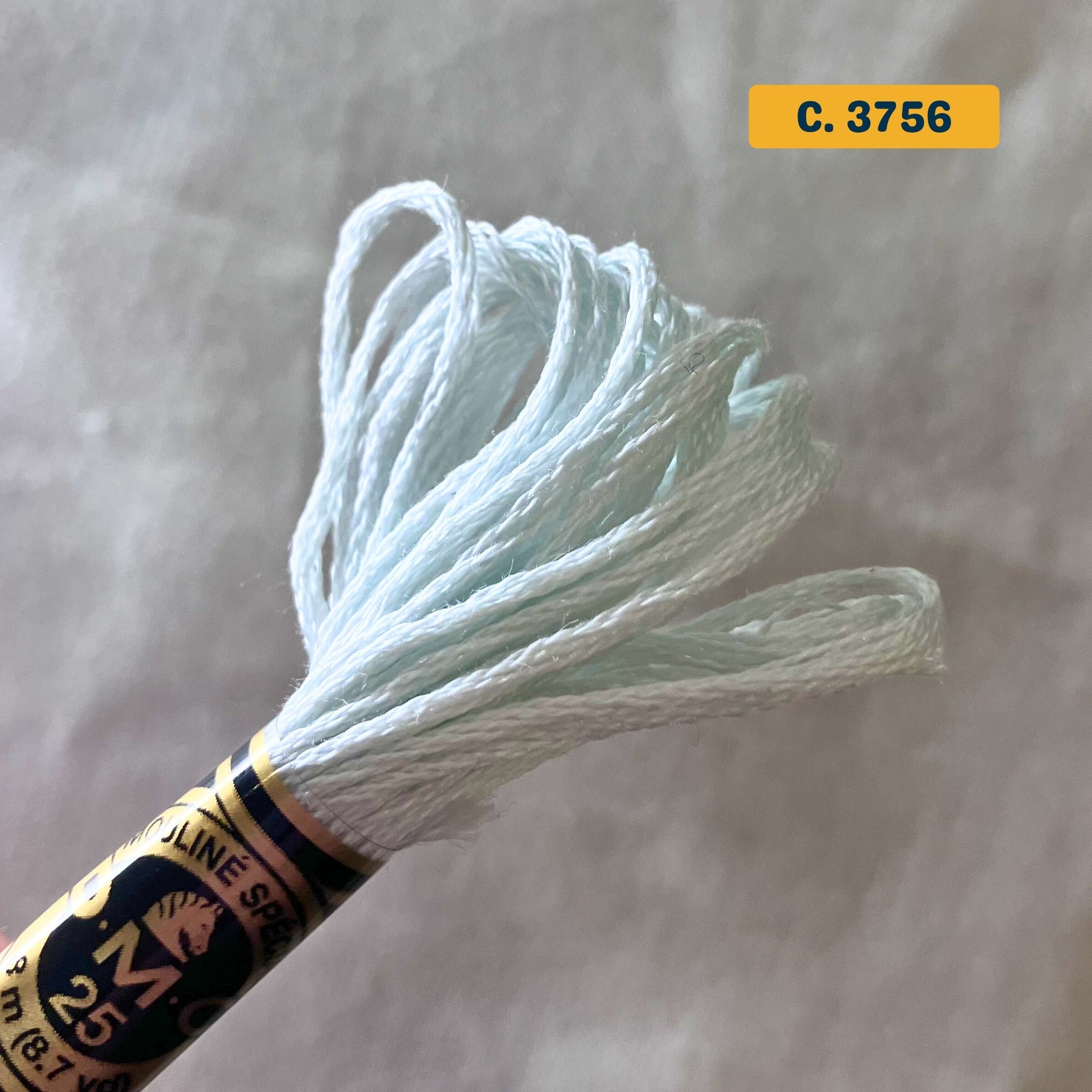 DMC 6-Strand Cotton Embroidery Floss – 3756 Very Pale Blue – 8m skein, 100% Egyptian cotton. Fabric background (blurred).