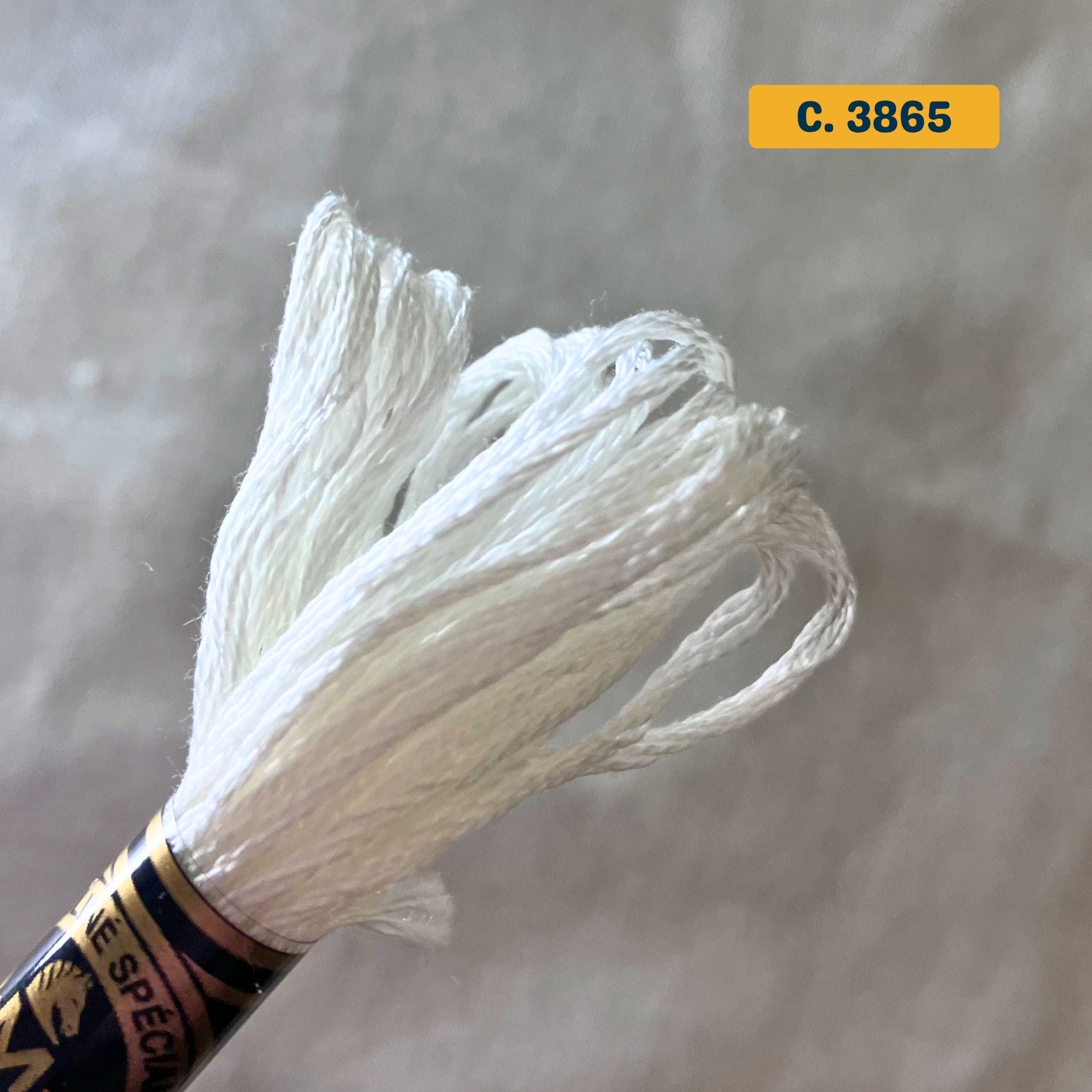 DMC 6-Strand Cotton Embroidery Floss – 3865 Bleached White – 8m skein, 100% Egyptian cotton. Fabric background (blurred).
