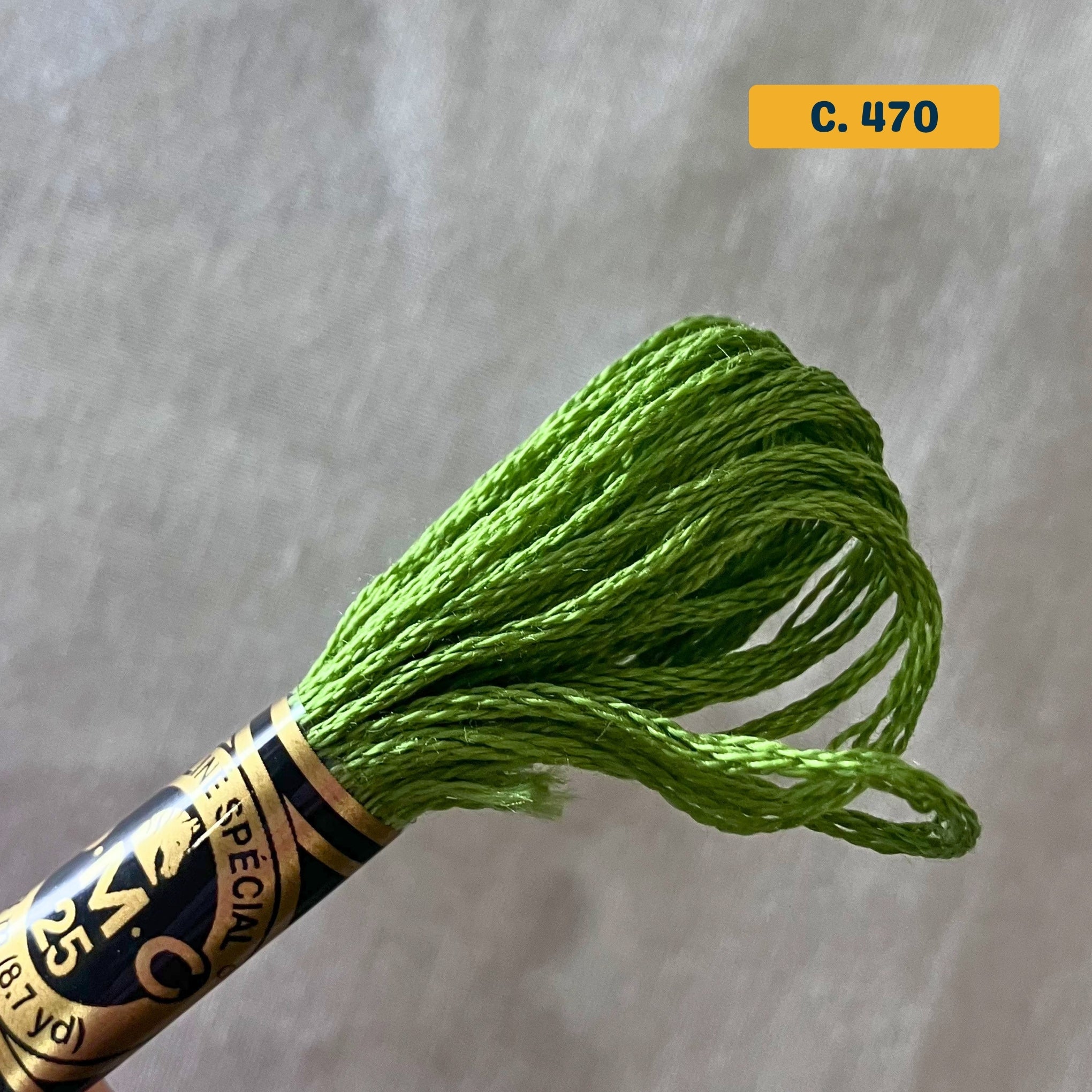 DMC 6-Strand Cotton Embroidery Floss – 470 Medium Green – 8m skein, 100% Egyptian cotton. Fabric background (blurred).