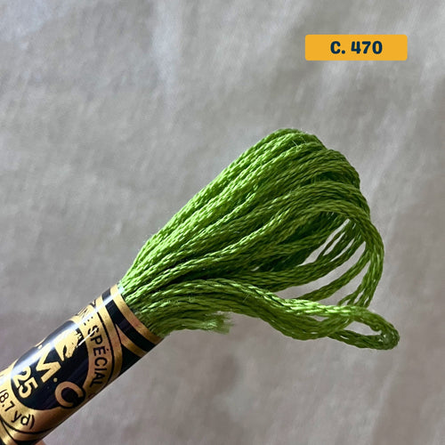 DMC 6-Strand Cotton Embroidery Floss – 470 Medium Green – 8m skein, 100% Egyptian cotton. Fabric background (blurred).