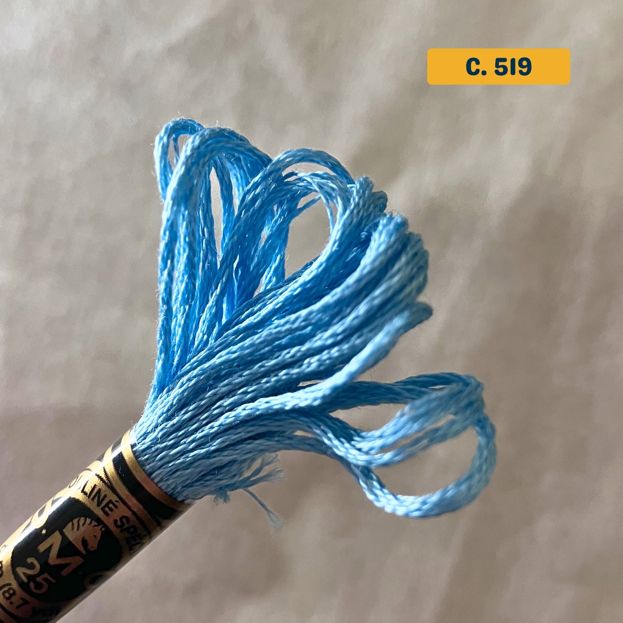 DMC 6-Strand Cotton Embroidery Floss – 519 Medium Blue – 8m skein, 100% Egyptian cotton. Fabric background (blurred).