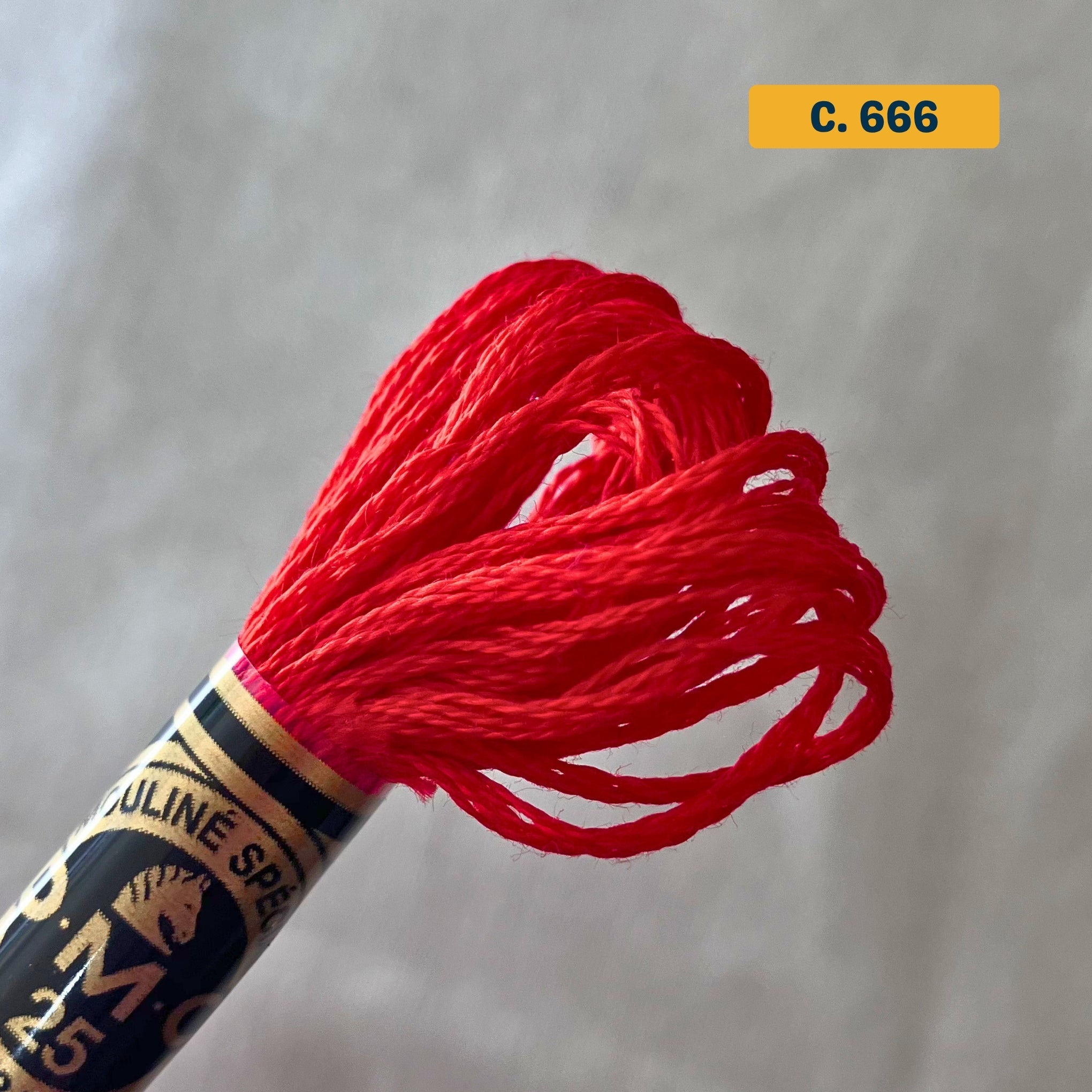 DMC 6-Strand Cotton Embroidery Floss – 666 Bright Red – 8m skein, 100% Egyptian cotton. Fabric background (blurred).