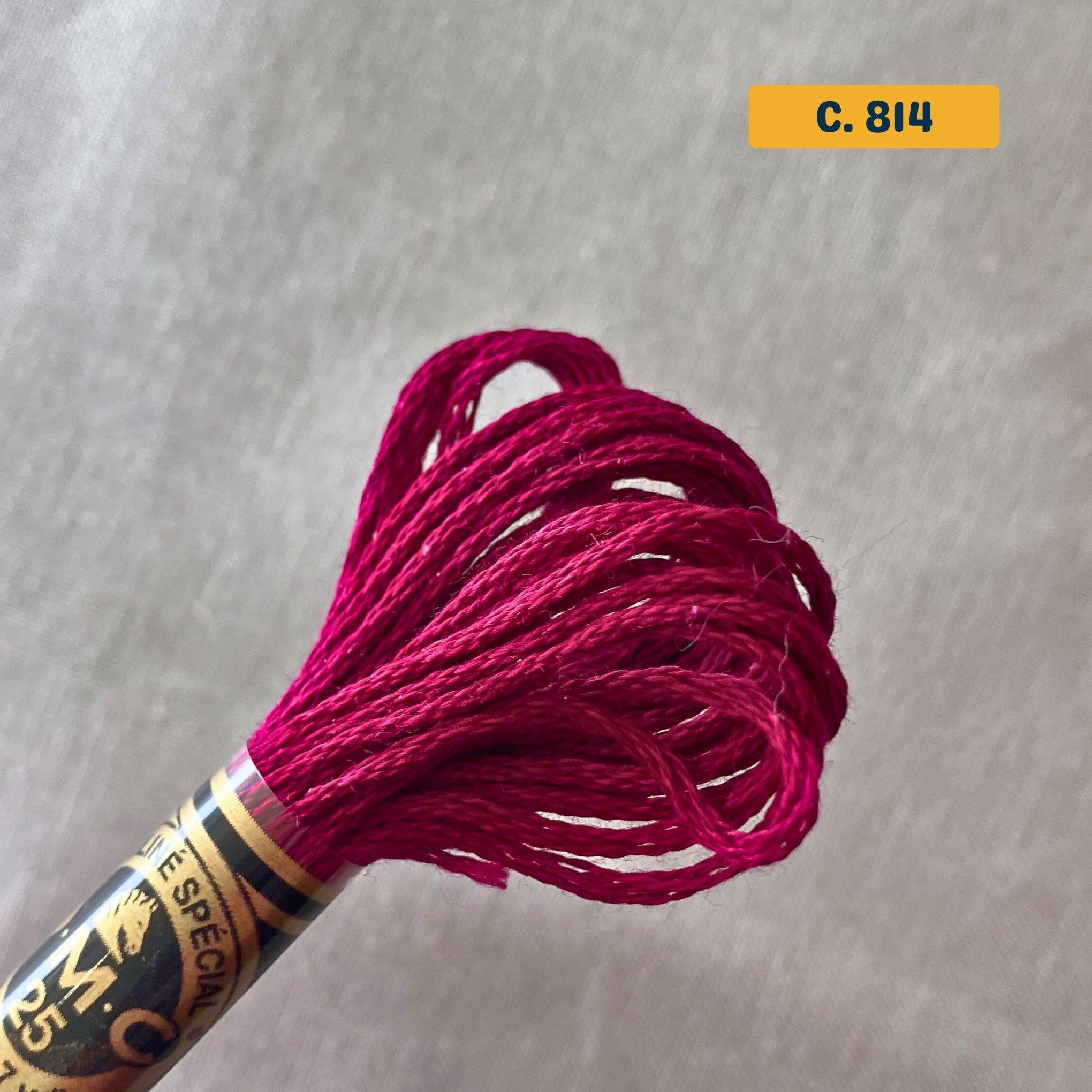 DMC 6-Strand Cotton Embroidery Floss – 814 Dark Red – 8m skein, 100% Egyptian cotton. Fabric background (blurred).