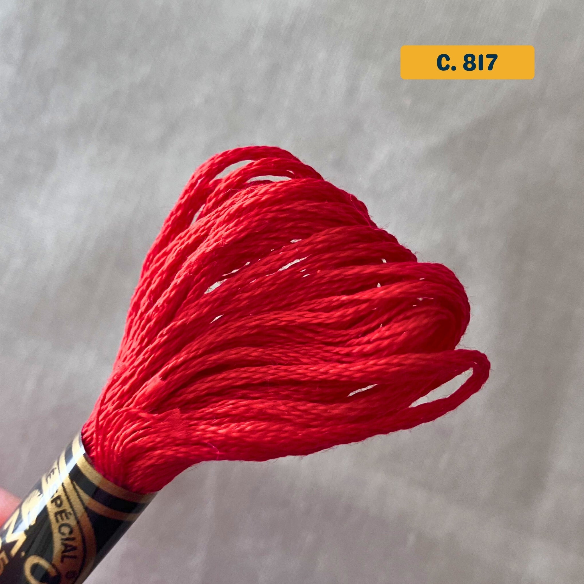 DMC 6-Strand Cotton Embroidery Floss – 817 Bright Red – 8m skein, 100% Egyptian cotton. Fabric background (blurred).