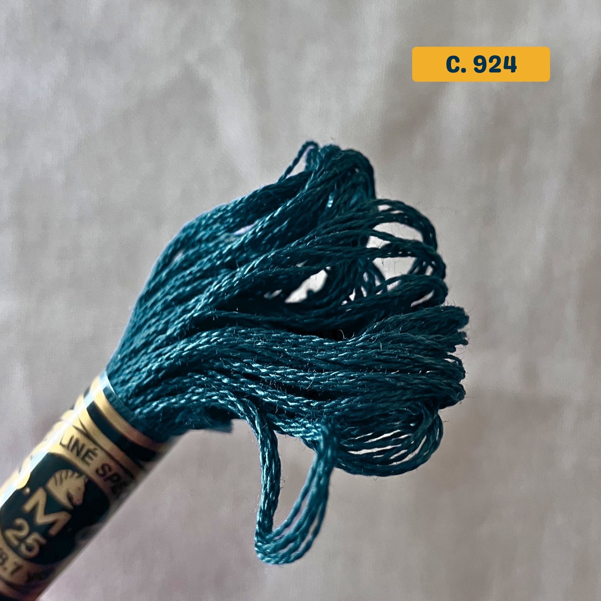 DMC 6-Strand Cotton Embroidery Floss – 924 Dark Turquoise – 8m skein, 100% Egyptian cotton. Fabric background (blurred).