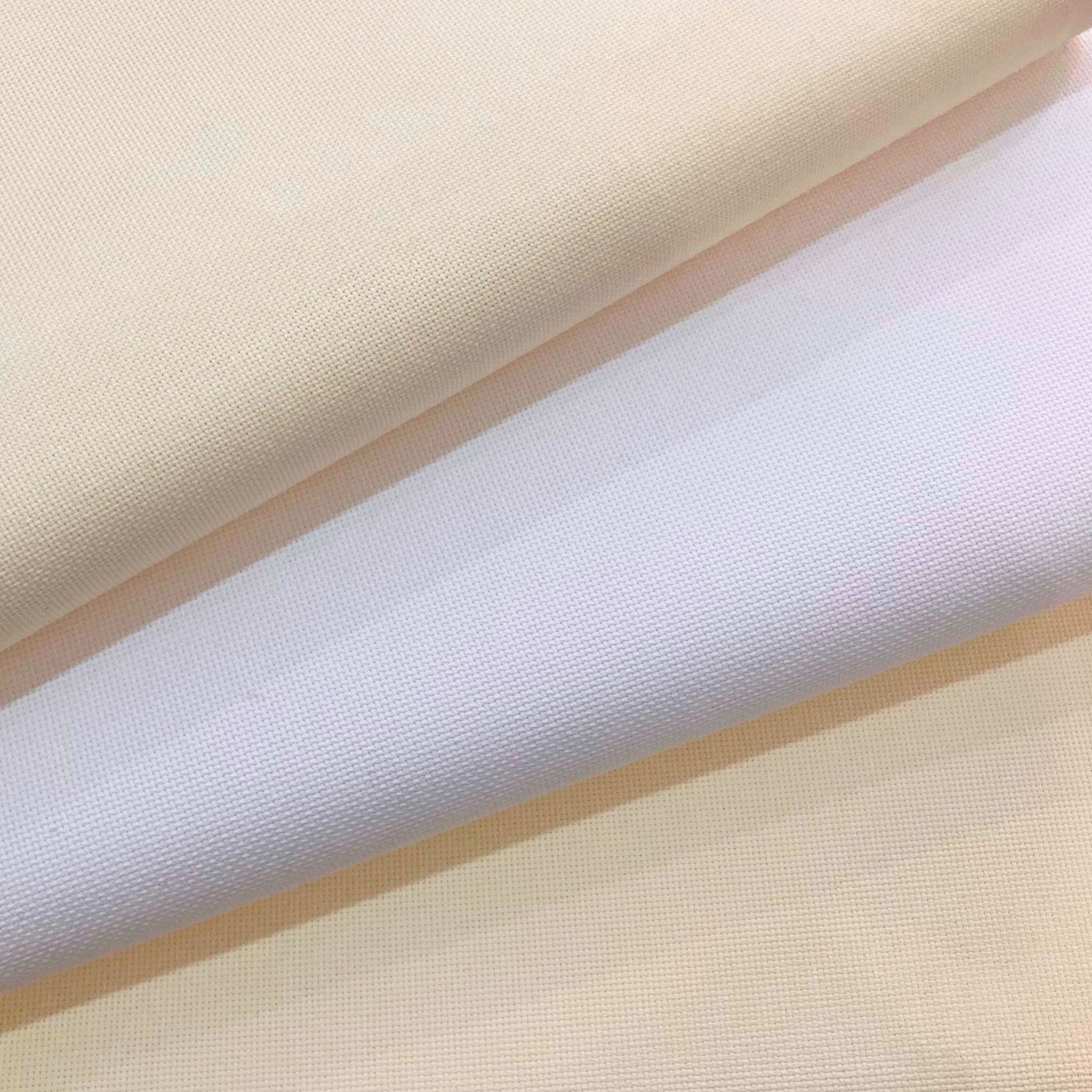 Colour comparisons — cool white vs warm cream (antique white) AIDA cloth. Close up on antique white AIDA cloth, fabric for cross stitch — 100% cotton square weave fabric in whites, sold by the half metre