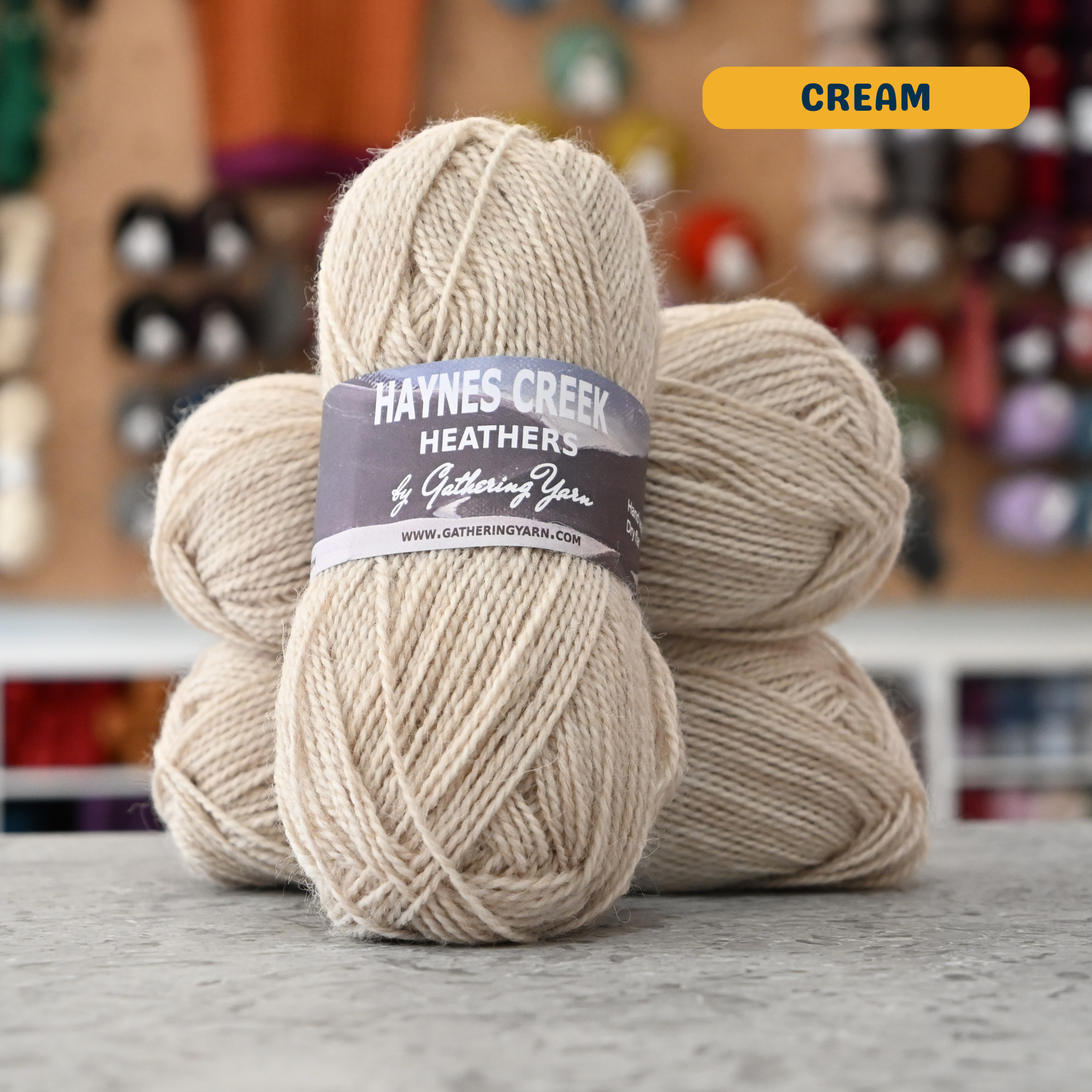 50g cream Peruvian highland wool DK yarn, 'Haynes Creek Heathers by Gathering Yarn' label visible, craft shop background (blurred)