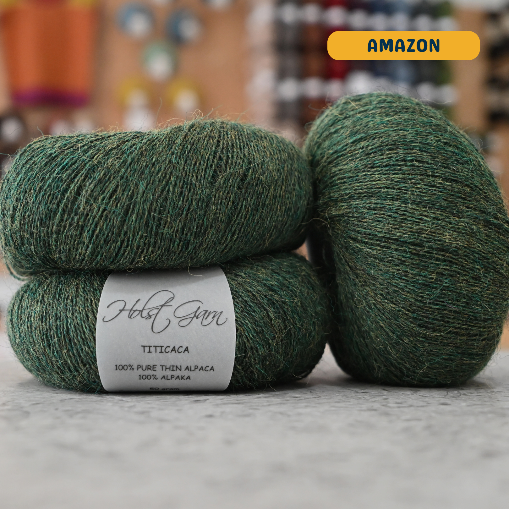 50g dark green (amazon) alpaca lace yarn, 'Holst Garn Titicaca 100% Pure Thin Alpaca' label visible, craft shop background (blurred)
