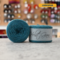 50g vibrant blue (larkspur) merino & shetland wool light fingering yarn, 'Holst Garn' label visible, craft shop background (blurred)