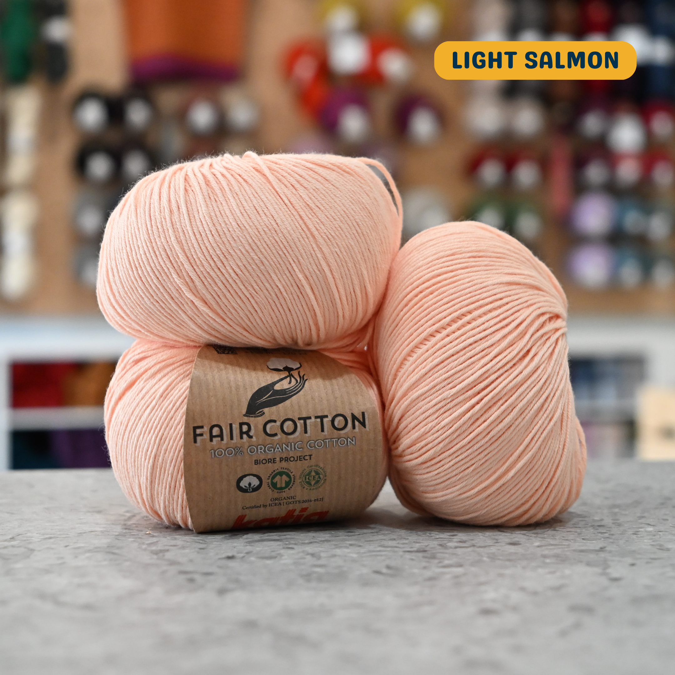 50g light salmon organic cotton sport yarn, 'Fair Cotton 100% Organic Cotton Katia' label visible, craft shop background (blurred)