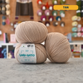 50g tan extrafine merino aloe vera sport yarn, 'Lana Gatto Baby Soft' label visible, craft shop background (blurred)
