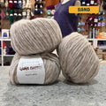 50g sand extrafine merino cotton baby alpaca bulky yarn, 'Luxury Lana Gatto Made In Italy Natura' label visible, craft shop background (blurred)