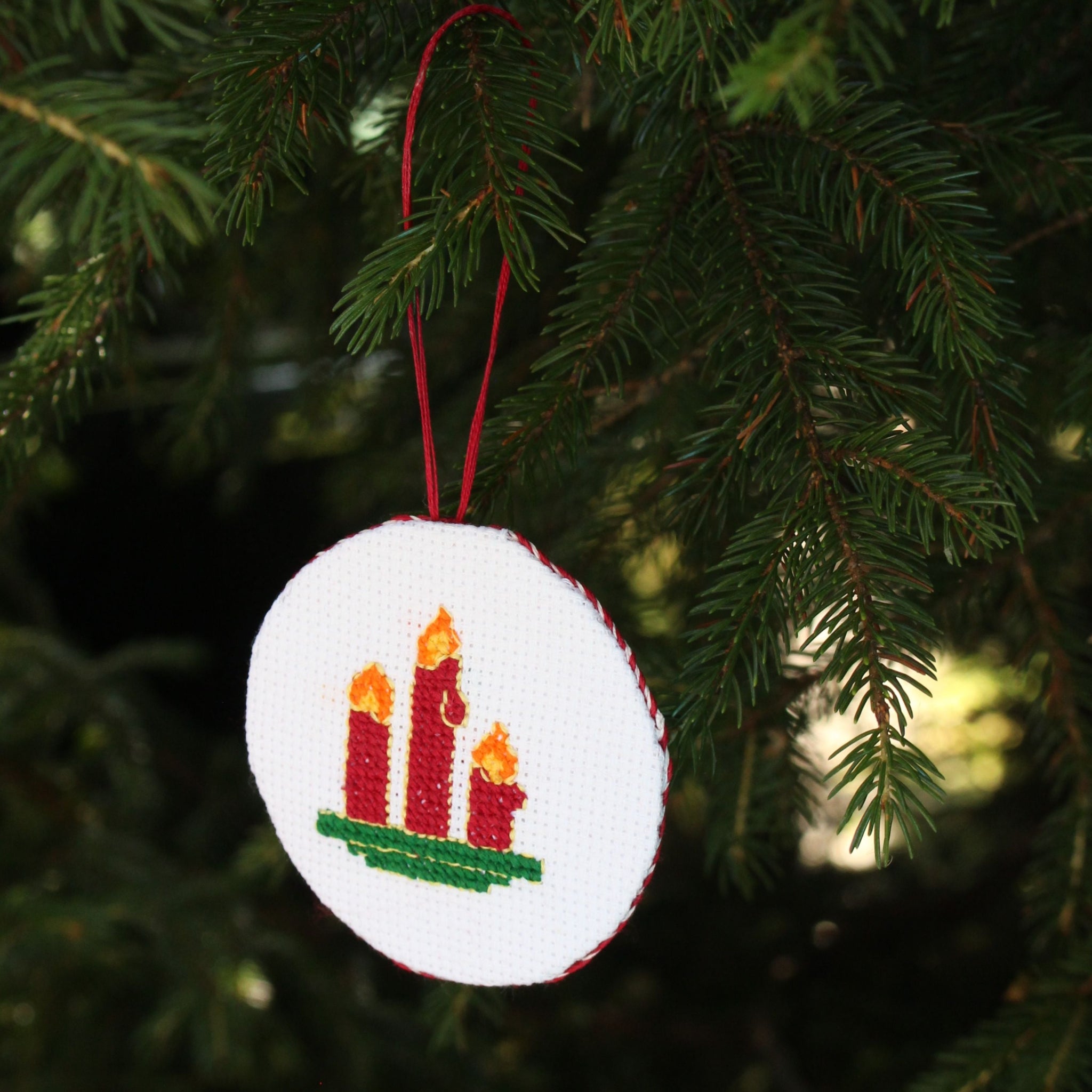 Sample for Learn to Cross Stitch Workshop. Halifax, Nova Scotia. A round white cross-stitched Christmas ornament.