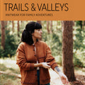 Book cover of 'Trails & Valleys' by Lindsey Fowler with a person wearing a hand-knit textured jacket in a forest setting. From Laine Publishing.