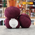 50g violet  merino & silk fingering yarn, 'Lise Tailor Merino Silk' label visible, craft shop background (blurred)