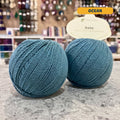 50g teal (ocean) cotton & cashmere sport yarn, 'Pascuali Sole Luxury Cotton Cashmere Blend' label visible, craft shop background (blurred)