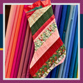 Sample image for quilting workshop. Halifax, Nova Scotia.
A handmade quilted Christmas stocking with diagonal stripes of red, pink, green, and holiday fabrics, hanging in front of a colourful array of bolted quilting cotton fabrics.