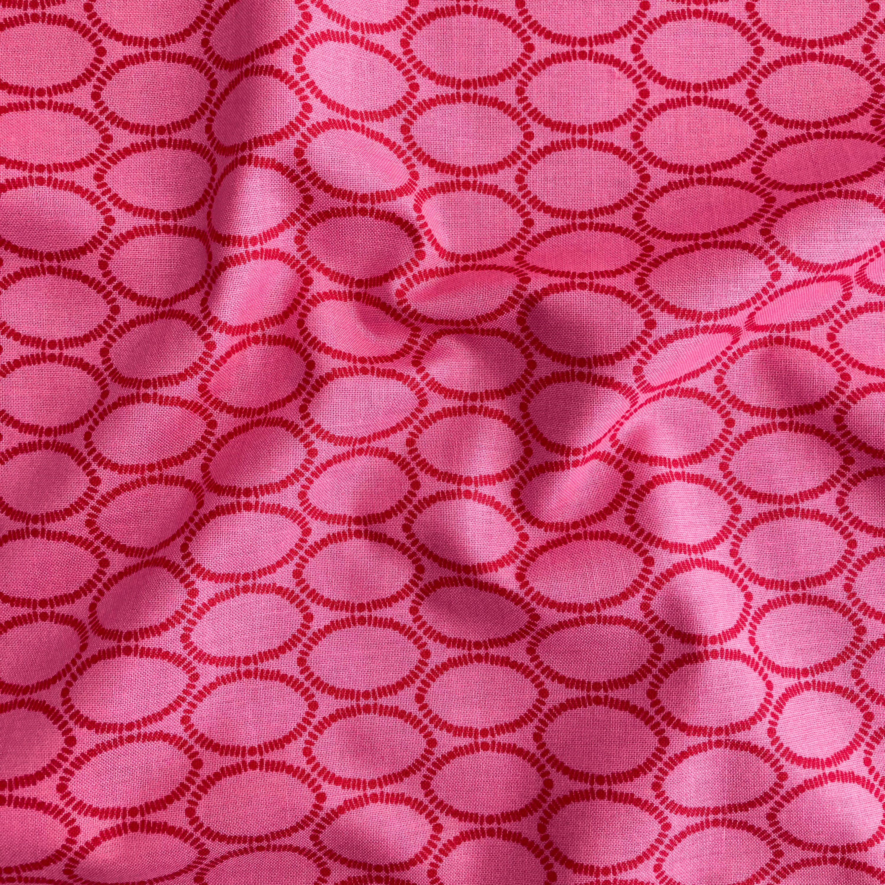 100% cotton quilting fabric — geometric ovals in red on a rich raspberry background. 44/45in width.