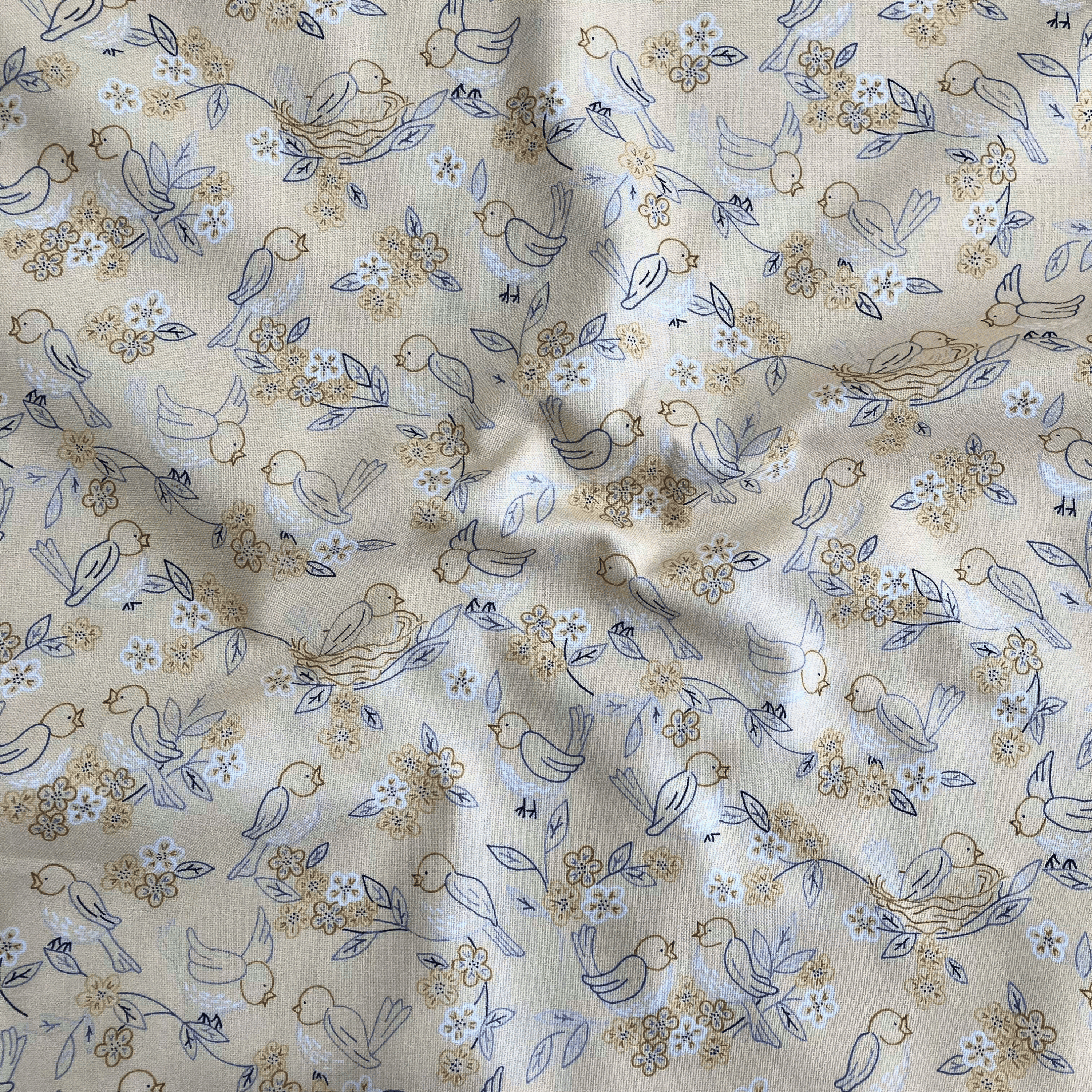 100% cotton quilting fabric — buttery yellow fabric with blue and grey line-drawn birds, nests, and blooms. 44/45in width.