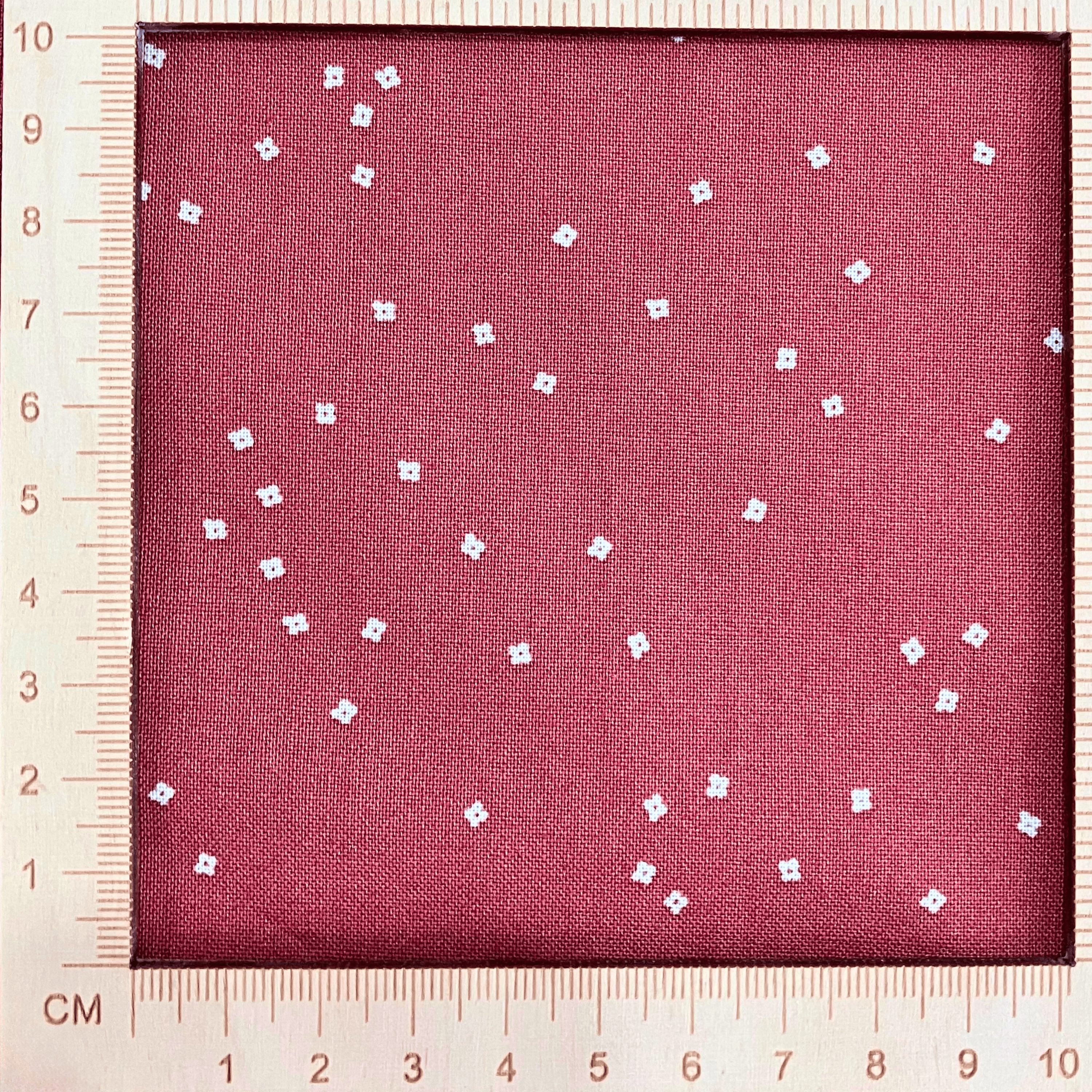 4"x4" scale —  100% cotton quilting fabric — warm red fabric with Tiny white confetti blossoms. 44/45in width.