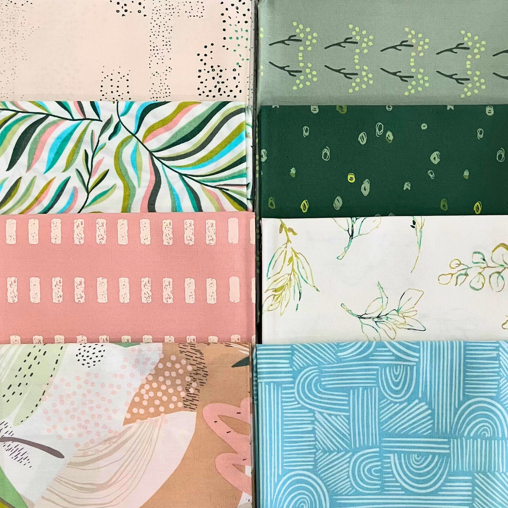Close up on 100% cotton quilting fabric — set of eight fat quarters — various fabrics with florals, leaves, and organic textures patterns of soft pinks & greens.