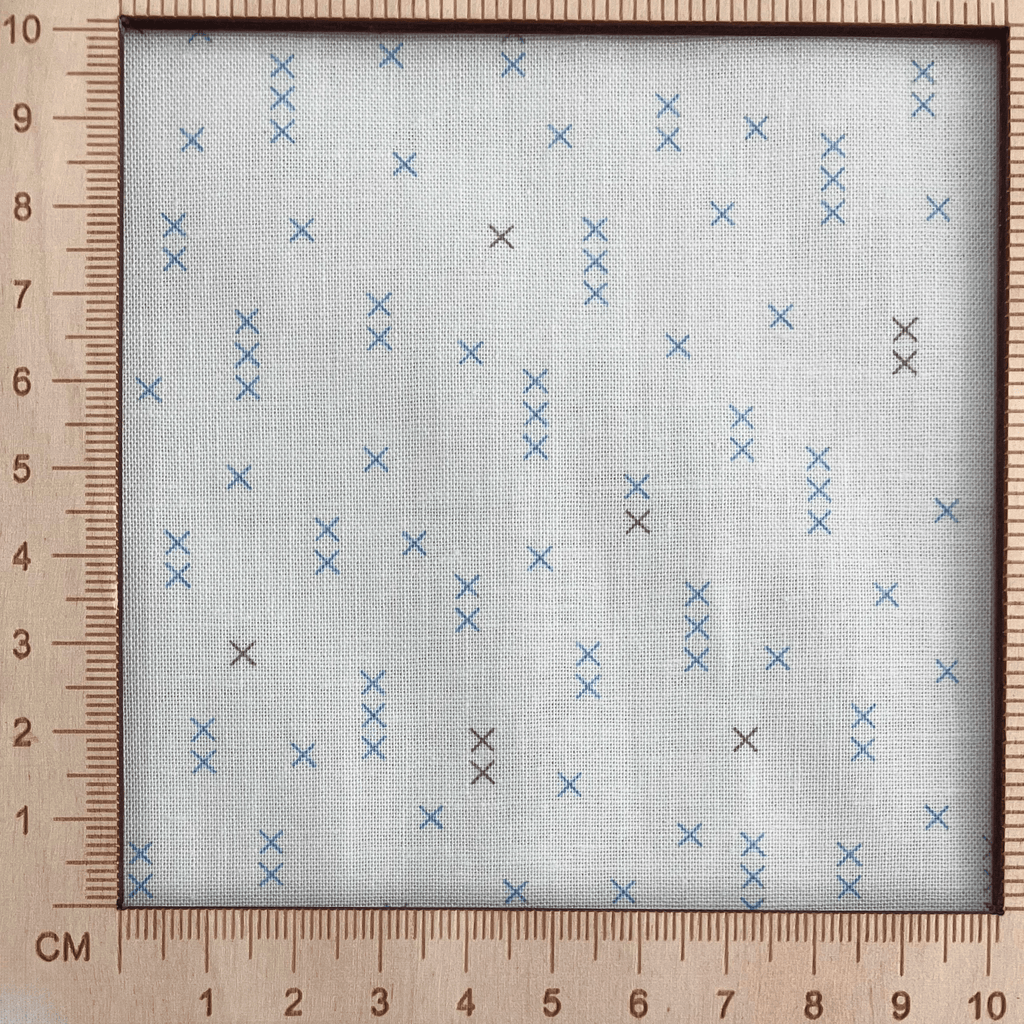 4"x4" scale — 100% cotton quilting fabric — light beige fabric with grey and blue x’s. 44/45in width.