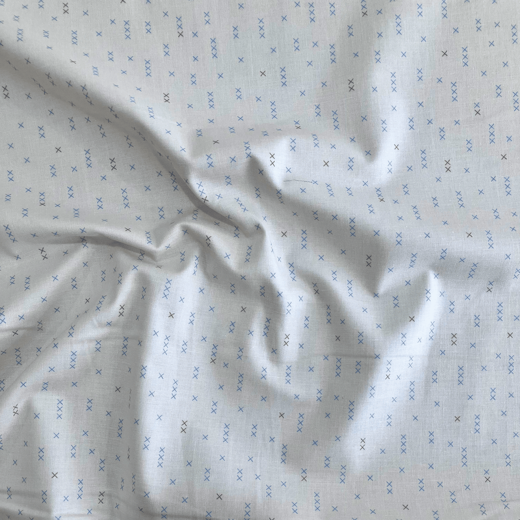 100% cotton quilting fabric — light beige fabric with grey and blue x’s. 44/45in width.