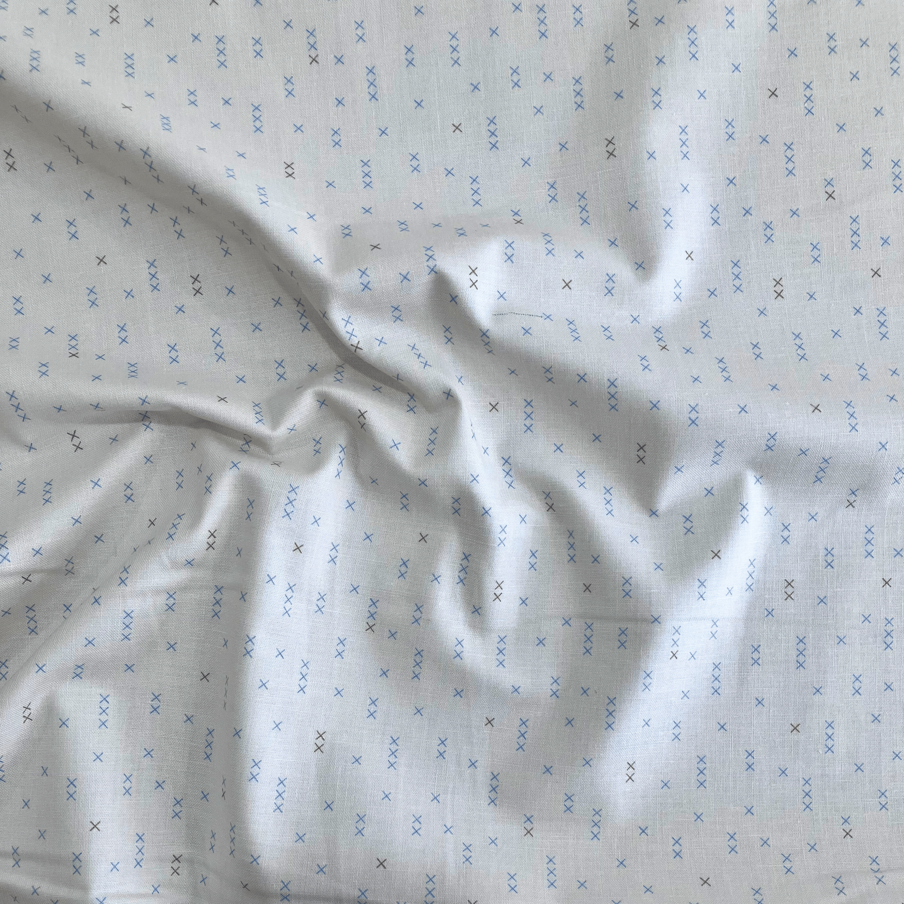 100% cotton quilting fabric — light beige fabric with grey and blue x’s. 44/45in width.