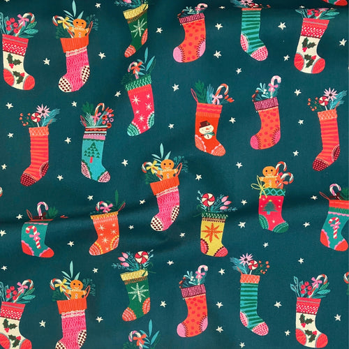 Christmas Stockings quilting cotton — illustrated Christmas stockings stuffed with candy canes and gingerbread on a deep teal background with white stars. Dashwood Studio, 44/45″ wide.