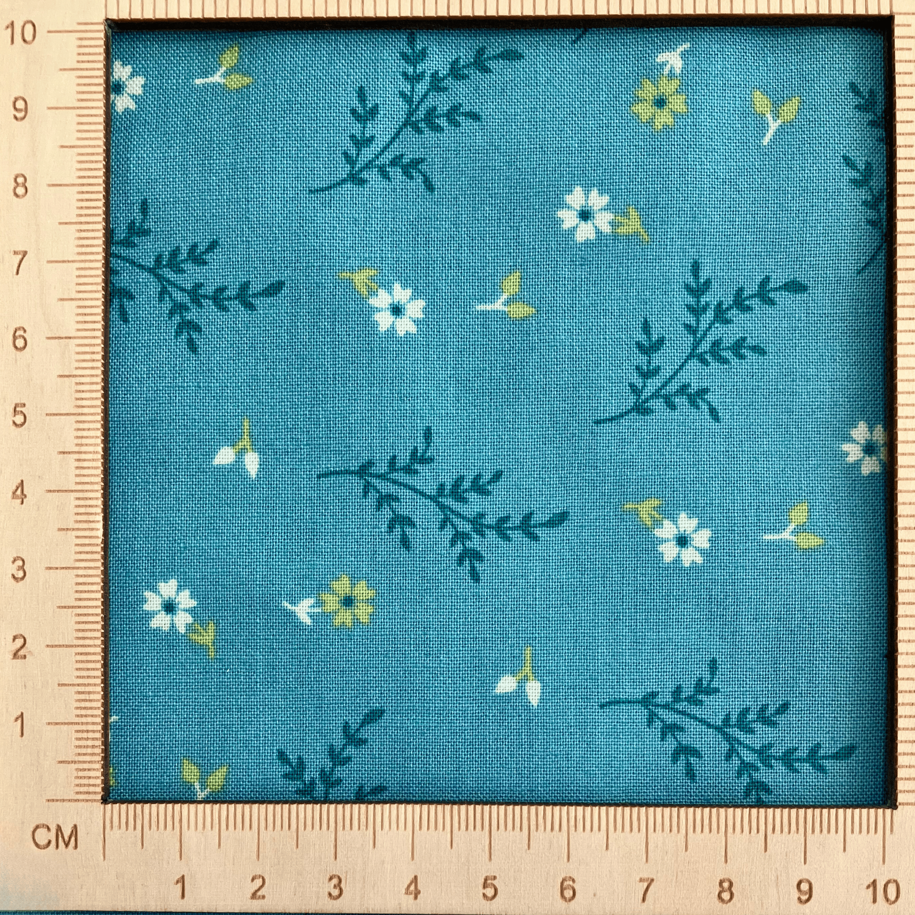4"x4" scale — 100% cotton quilting fabric — white flowers & green leaves on teal. 43/44in width.