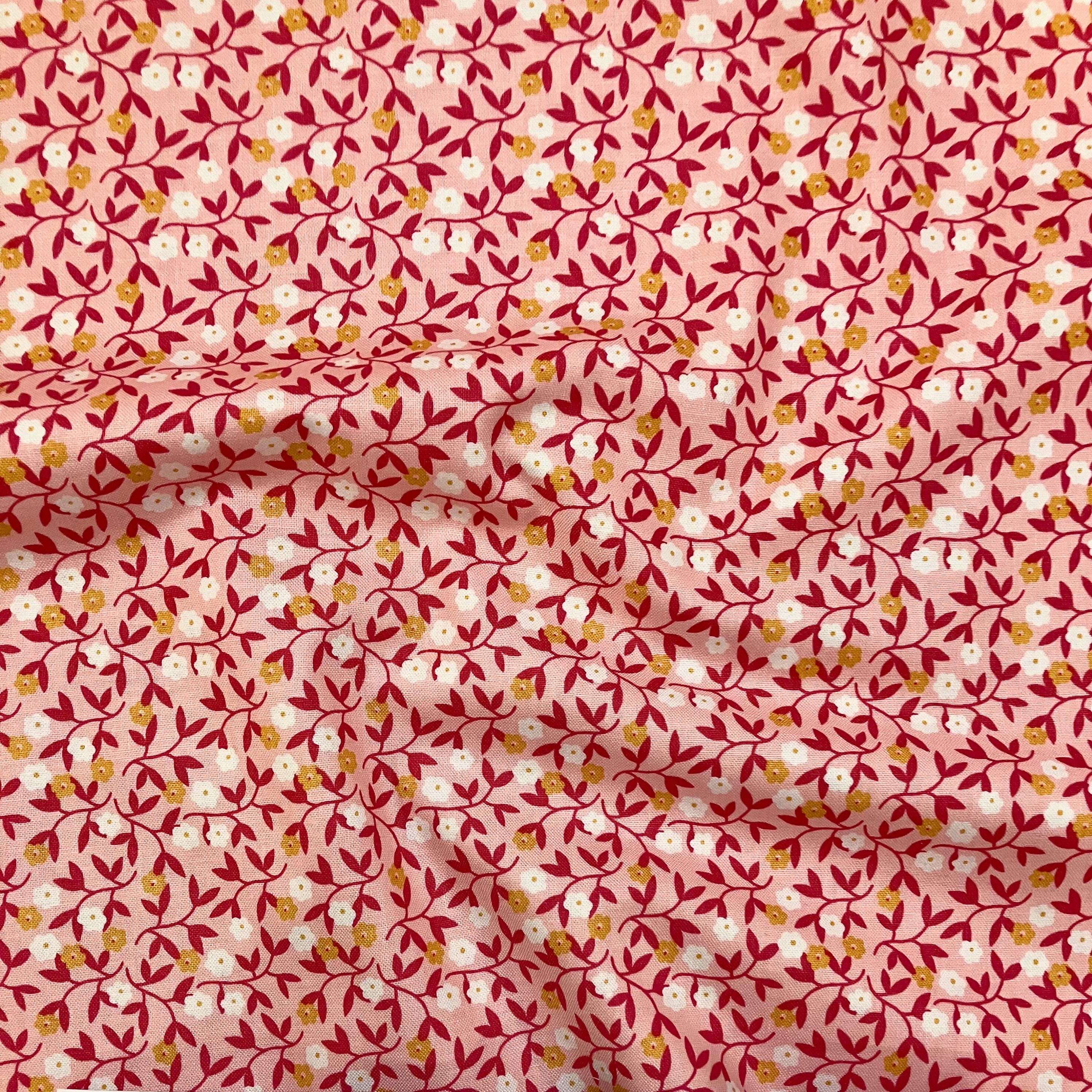 100% cotton quilting fabric — small white & orange flowers on light coral. 43/44in width.