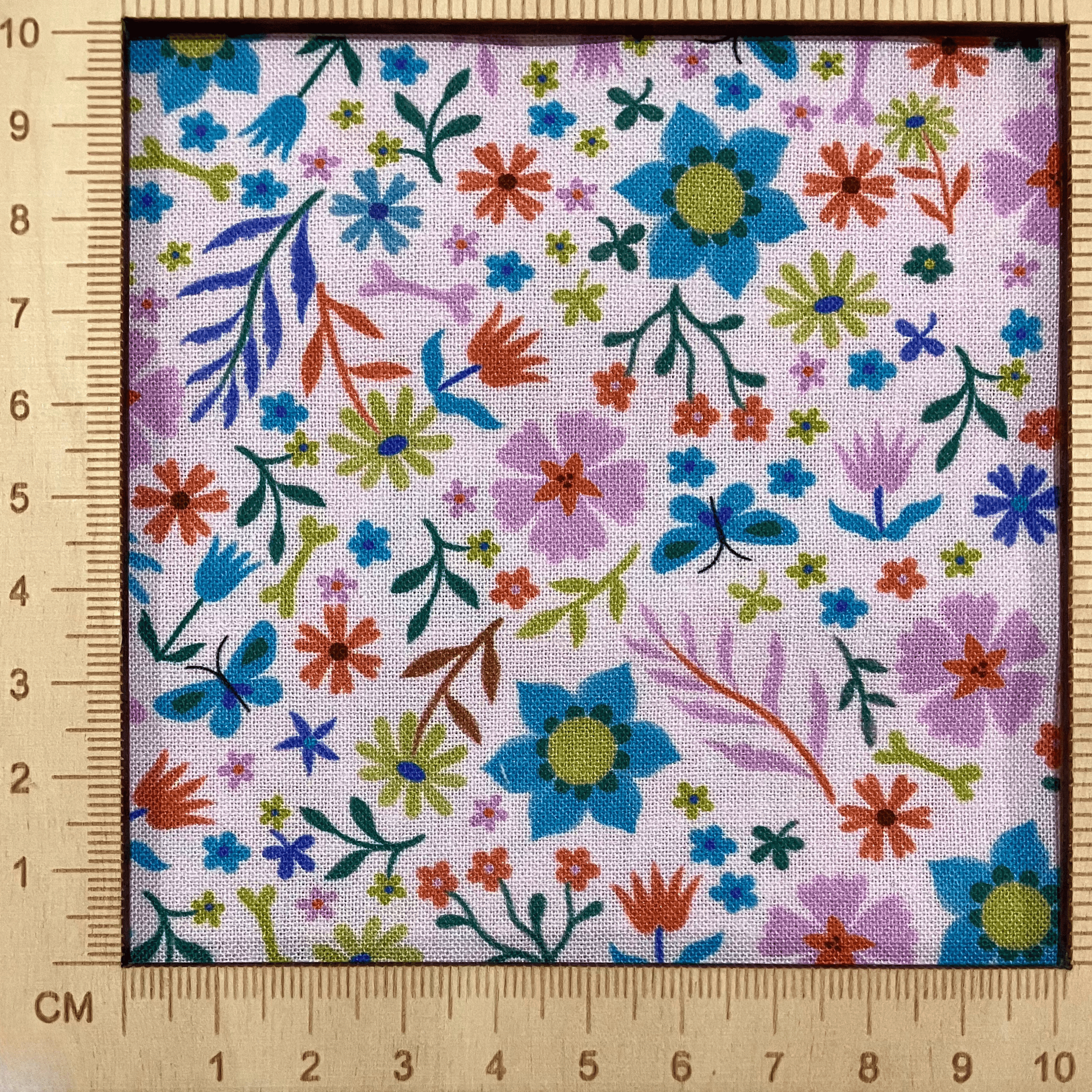 4"x4" scale — 100% cotton quilting fabric — colourful floral pattern on a pale pink. 43/44in width.
