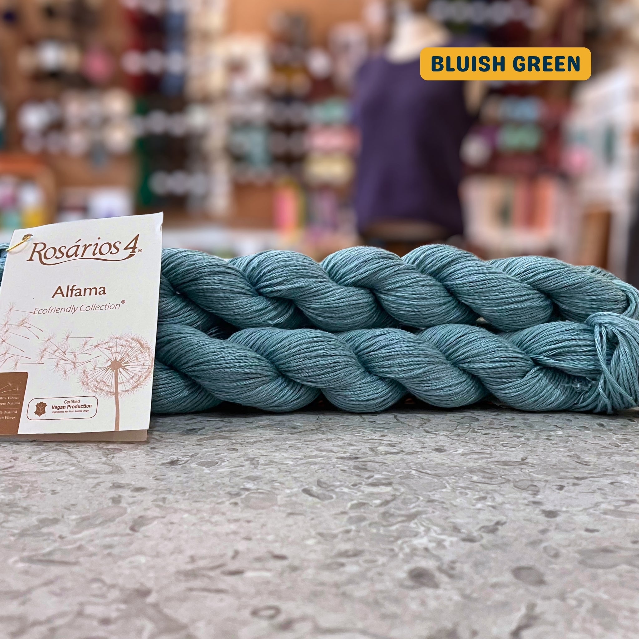 50g turquoise (bluish green) pure linen dk yarn, 'Rosários4 Alfama Ecofriendly Collection' label visible, craft shop background (blurred)
