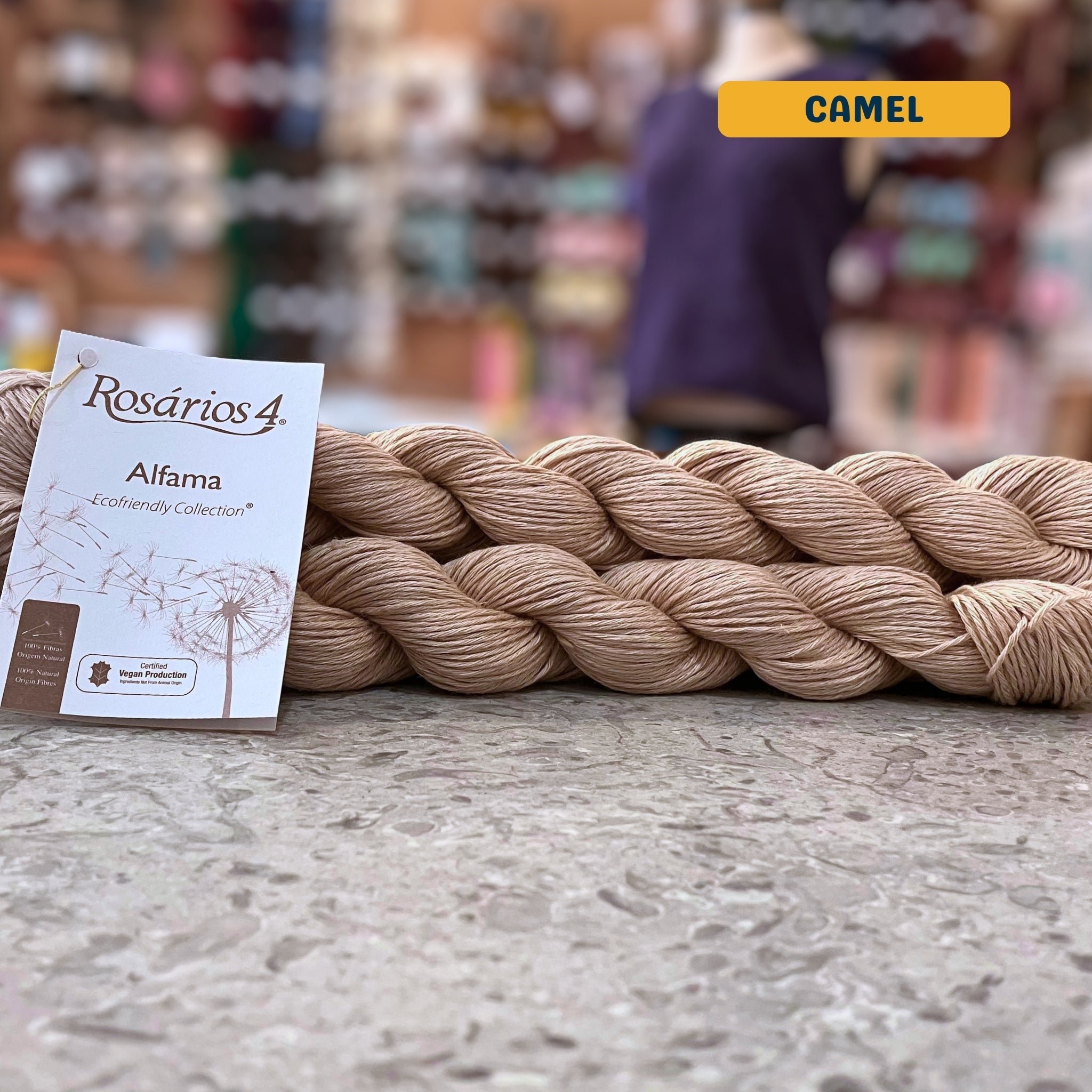 50g beige (camel) pure linen dk yarn, 'Rosários4 Alfama Ecofriendly Collection' label visible, craft shop background (blurred)