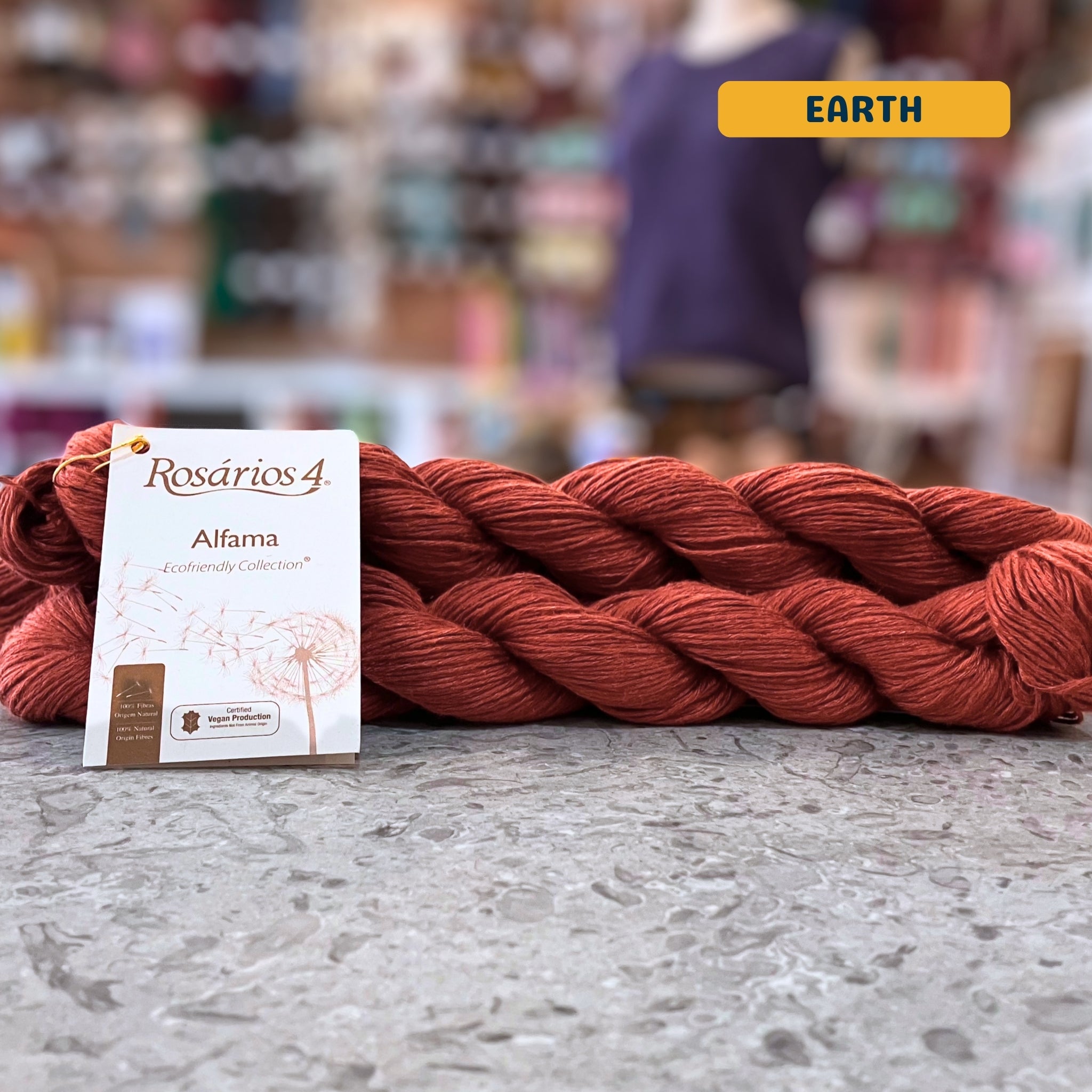 50g rust orange (earth) pure linen dk yarn, 'Rosários4 Alfama Ecofriendly Collection' label visible, craft shop background (blurred)