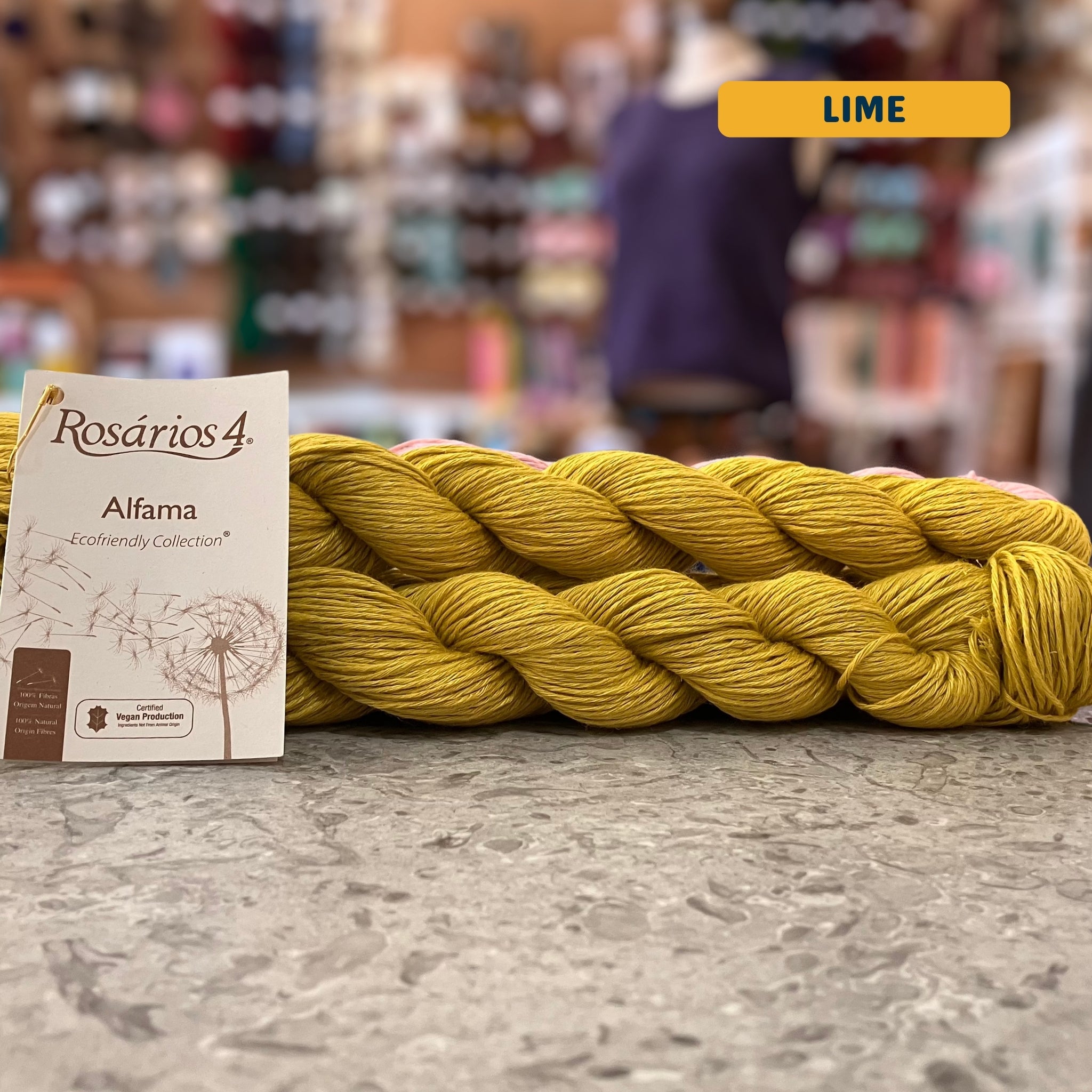 50g green-yellow (lime) pure linen dk yarn, 'Rosários4 Alfama Ecofriendly Collection' label visible, craft shop background (blurred)