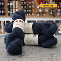 100g dark blue (aigrette) canadian wool fingering yarn, 'Waxwing Yarn Company Cèdre' label visible, craft shop background (blurred)