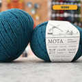 100g blue (1526G)  merino & manchega  wool yarn, 'Mota Wooldreamers 100% Wool' label visible, craft shop background (blurred)
