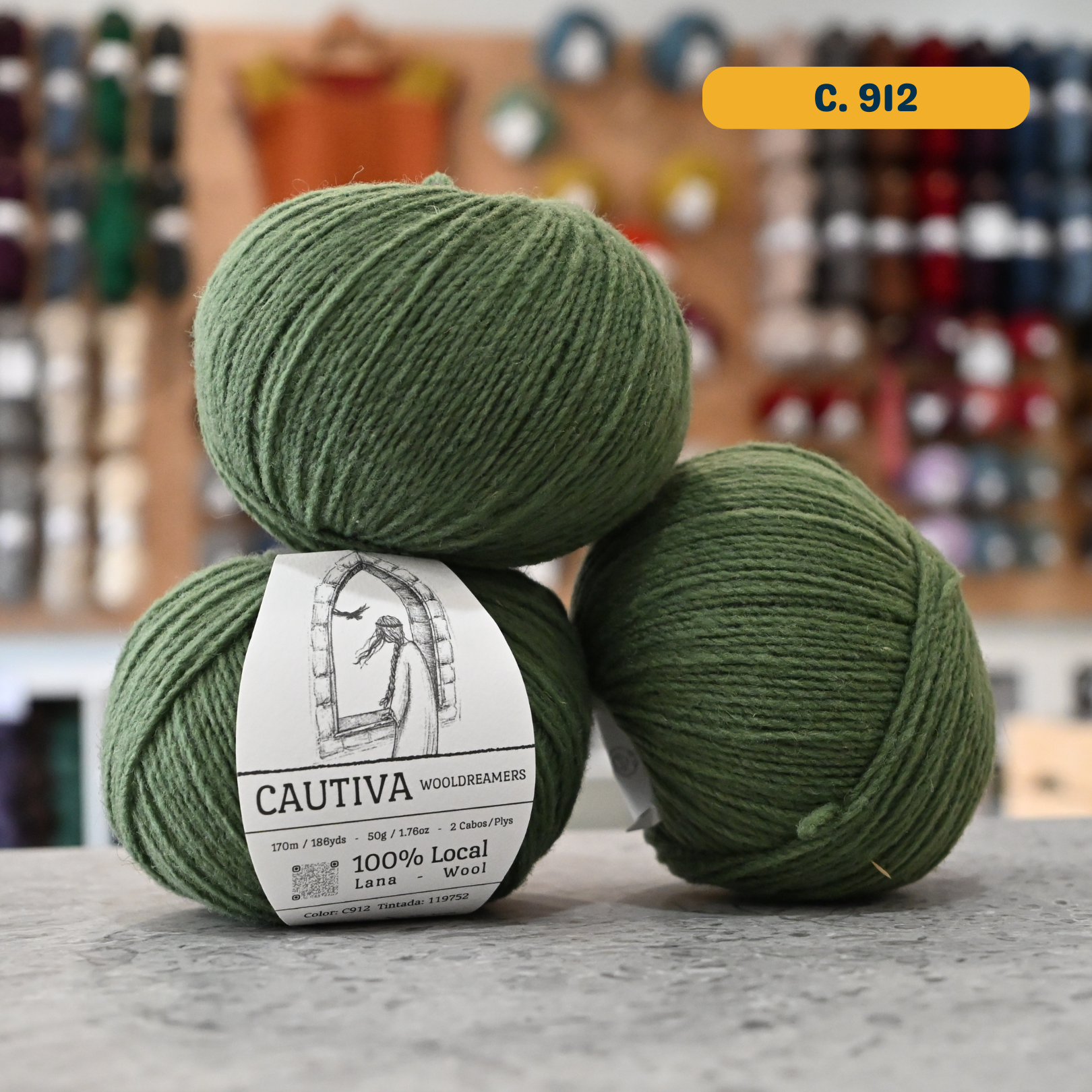 50g green (c. 912) merino & manchega wool sport yarn, 'Cautiva Wooldreamers  100% Wool' label visible, craft shop background (blurred)